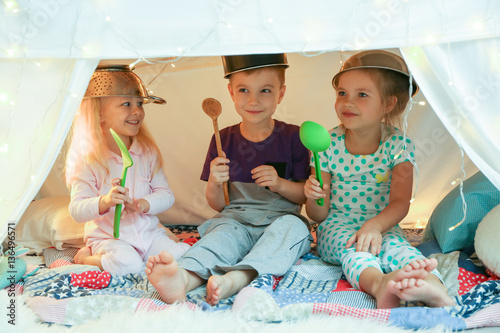 Fotografie Cute little children playing with kitchenware while sitting in hovel at home