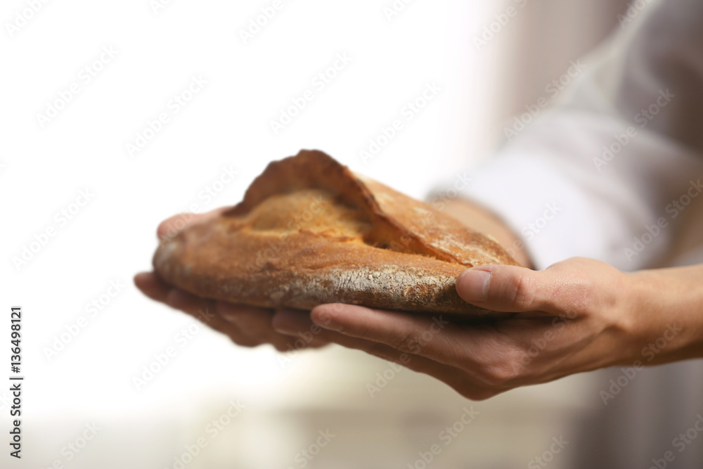 Fototapeta premium Male hands holding freshly baked rye bread, closeup