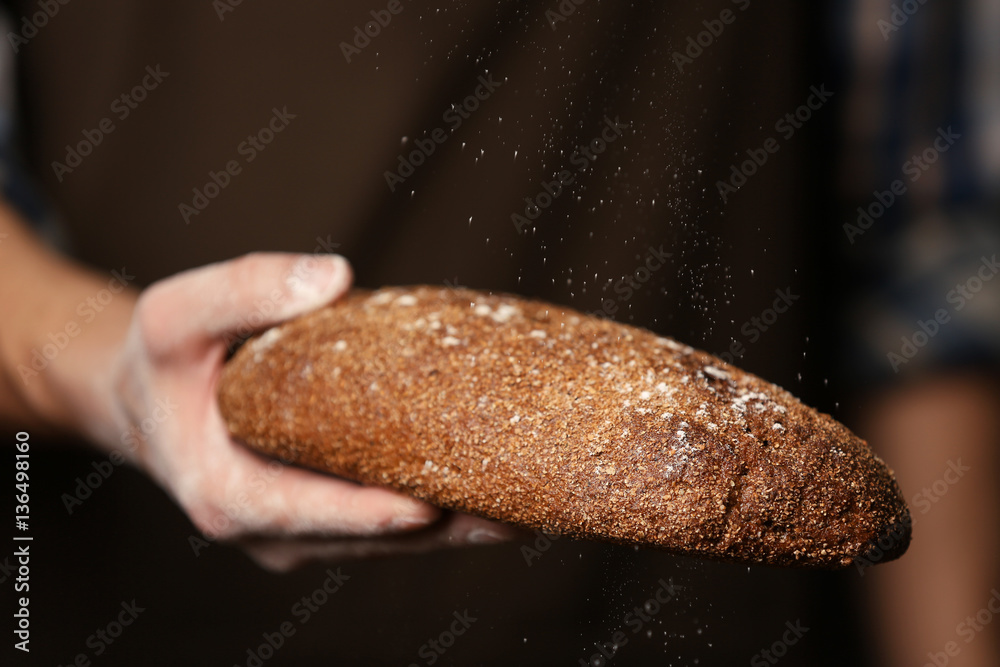Male hand holding freshly baked rye bread, closeup Male hand holding freshly baked rye bread, closeup