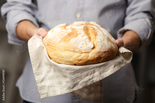 Male hands holding freshly baked wheaten bread, closeup