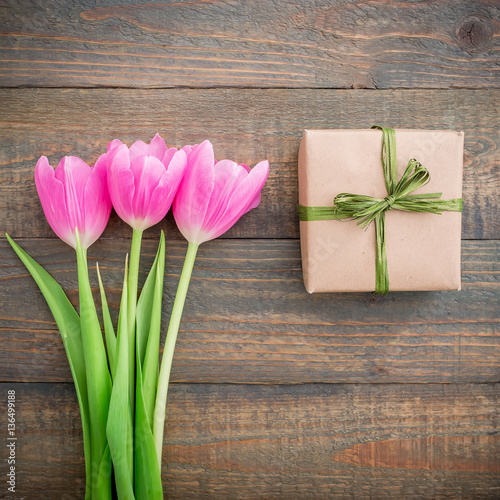 Tulip flowers and paper gift box on wood background. Flat lay, Top view. Woman day.