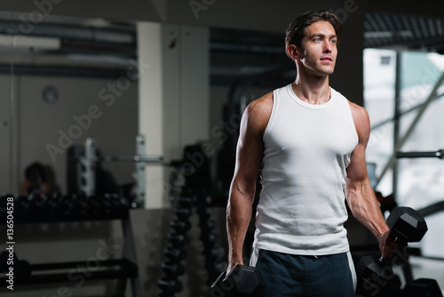 Young man working out with a dumbbell in gym