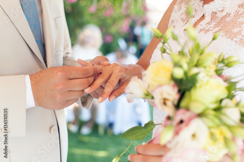 The groom wears a ring on the finger of the bride at a wedding photo