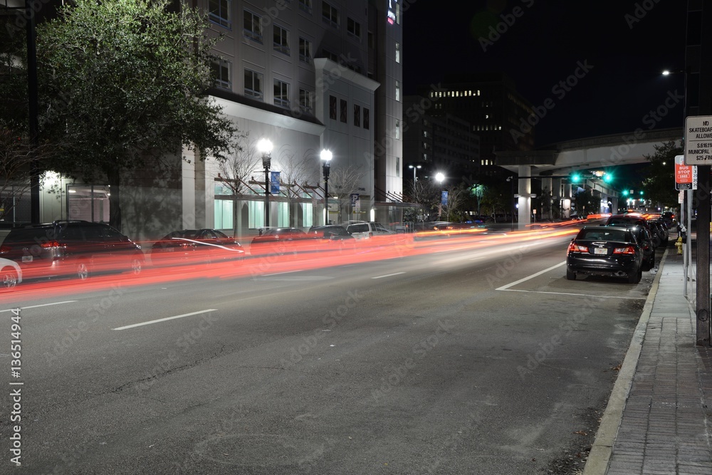 View of a busy city street at night showing cars zipping through shot at night from the sidewalk at night as long exposure, landscape composition