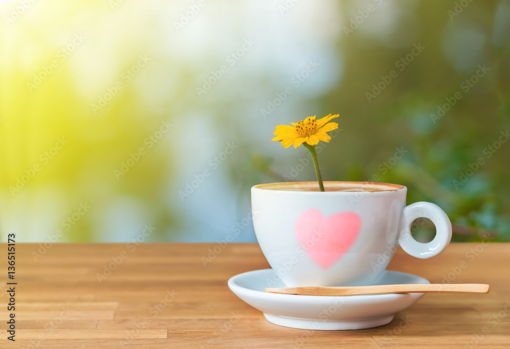 The yellow flower in a cup of coffee on wood table with light an The yellow flower in a cup of coffee on wood table with light an