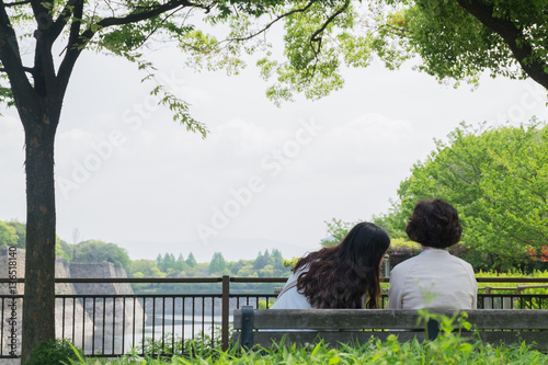 Obraz na płótnie Back of two women sitting and talking on wood bench w salonie