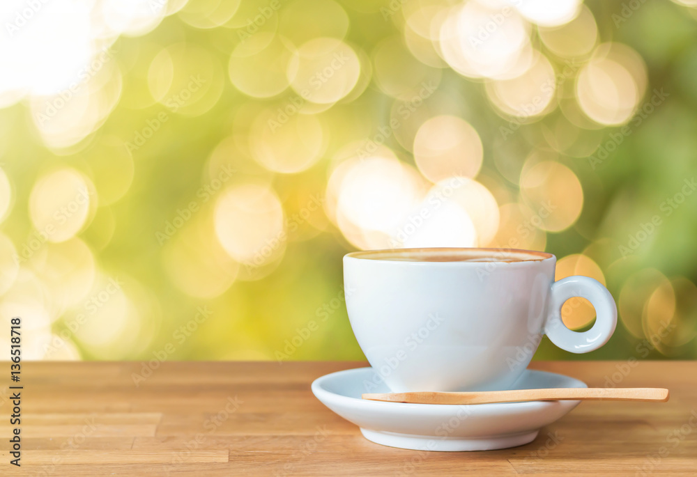 A cup of coffee on wood table with light and bokeh background