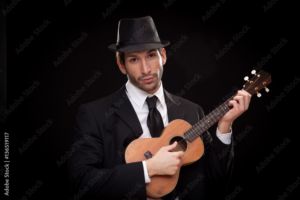 Obraz premium elegant happy man singer musician playing ukulele guitar isolated on black