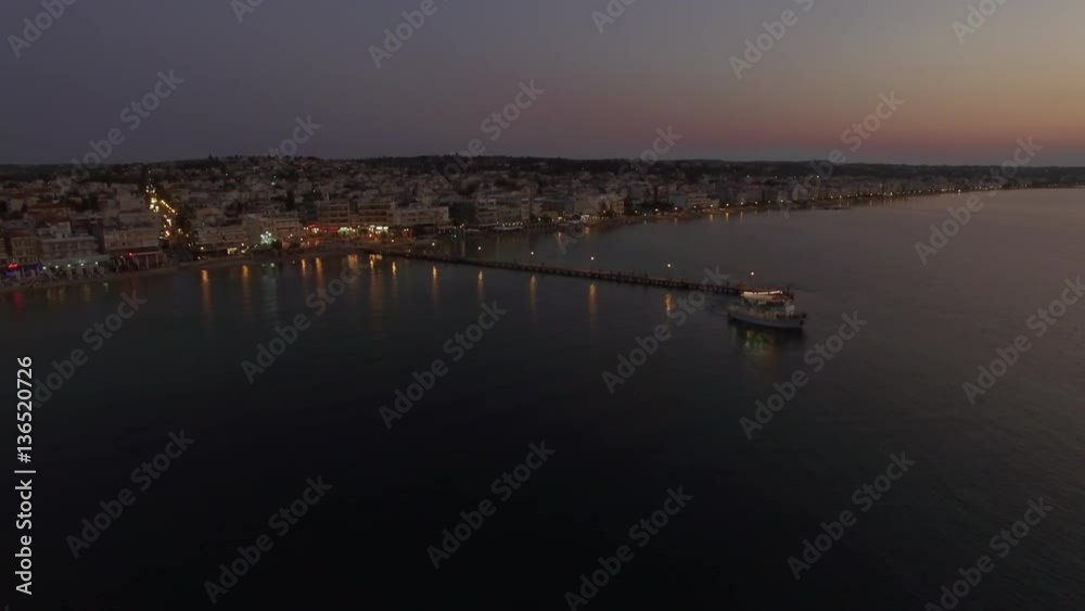 Aerial view of touristic boat leaving the pier and sailing in quiet sea in the dusk. Sea travel during vacation on resort in Thessaloniki, Greece Aerial view of touristic boat leaving the pier and sailing in quiet sea in the dusk. Sea travel during vacation on resort in Thessaloniki, Greece