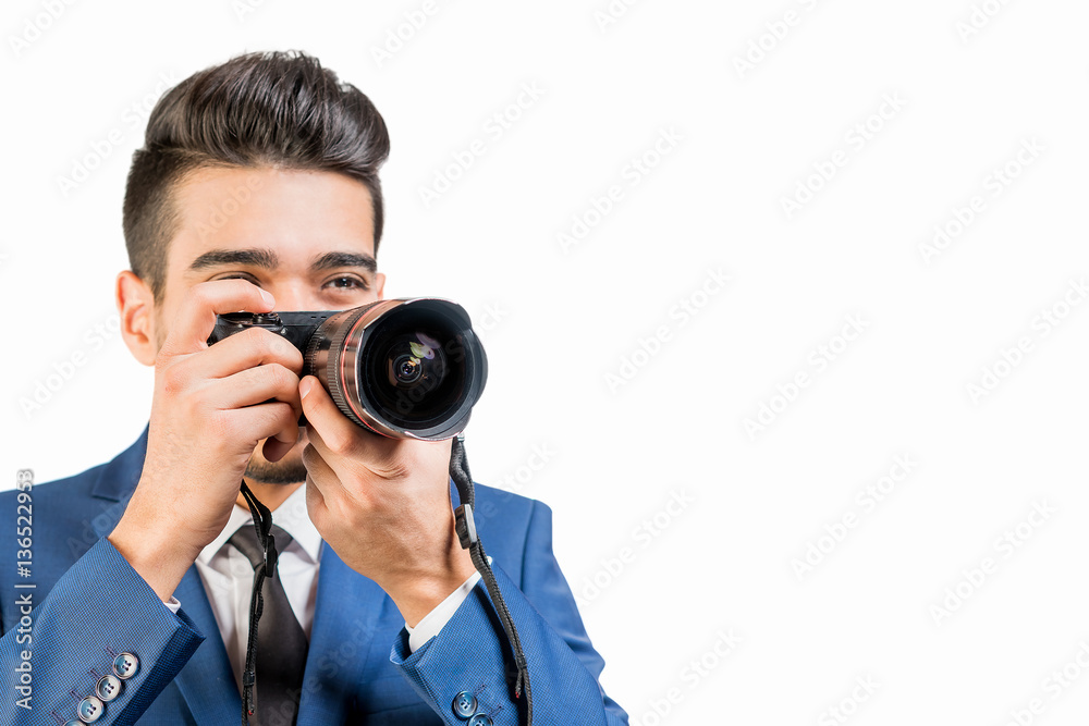 Young attractive man in a blue suit with a camera on a white background. Isolated Young attractive man in a blue suit with a camera on a white background. Isolated