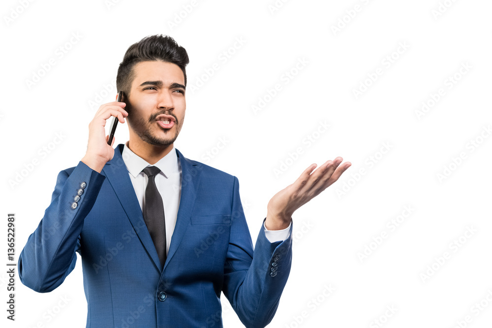 Young attractive man in a blue suit talking by the phone on a white background. Isolated Young attractive man in a blue suit talking by the phone on a white background. Isolated