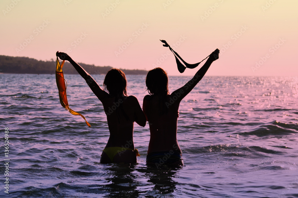 Fototapeta premium Two girls in ocean at sunset 