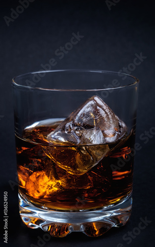 Whiskey with ice cubes on dark background