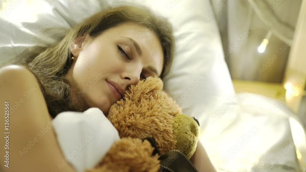 Girl sleeps in a bed with a toy a teddy bear 4k 20s