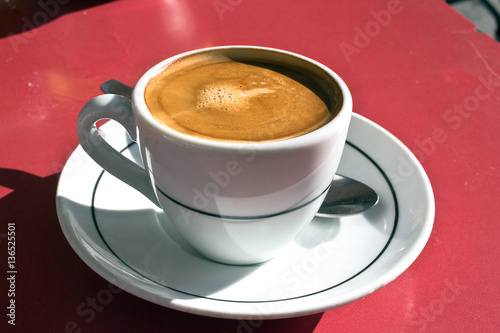 Hot espresso macchiato - cafè with a little milk. White coffe cup on outdoors table. Taken in Madrid