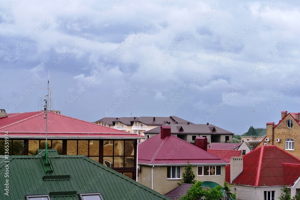 Roofs of rural houses on background cloudy rainy sky