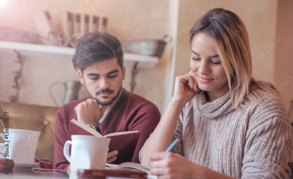 Young couple drinking coffee and reading a book in the cafe. Edu Young couple drinking coffee and reading a book in the cafe. Edu