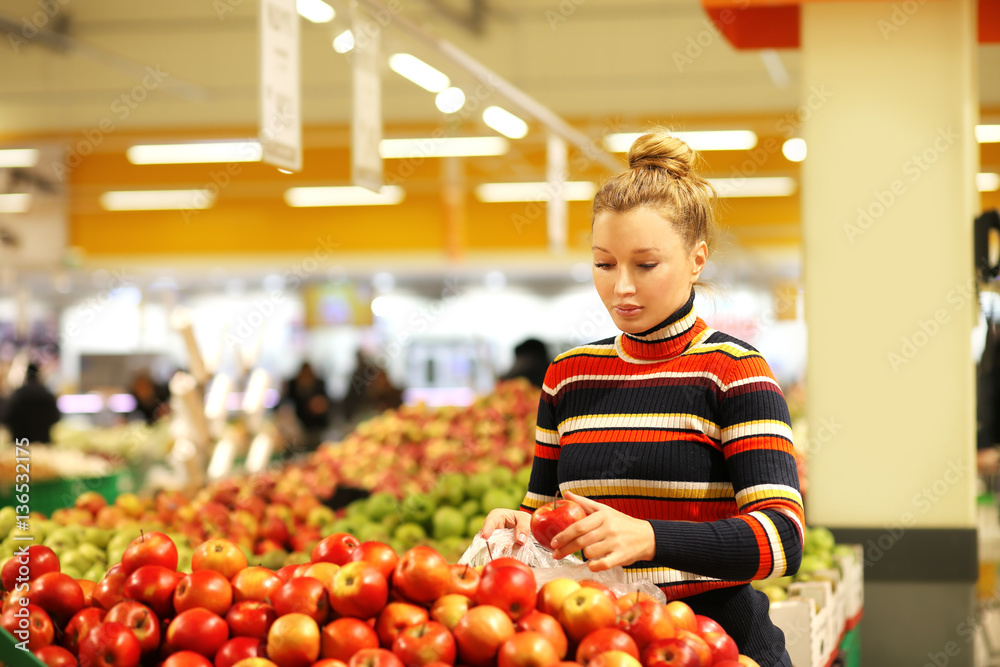 Fototapeta premium Middle-age woman buying apples at the market