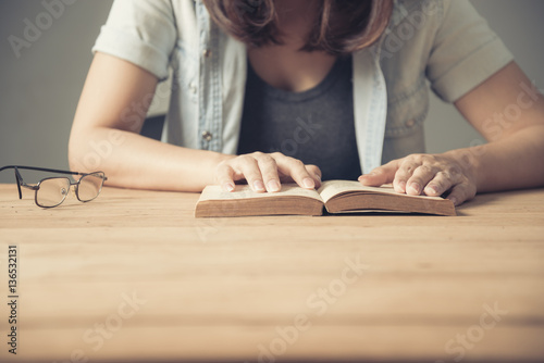 Young girl is sitting on table and reading a book
