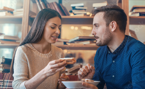 Couple in love. Young couple eating cake surrounded with books i
