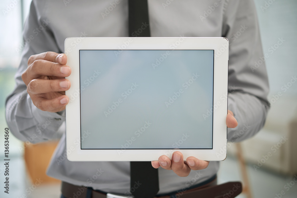 Close-up shot of businessman in shirt and tie showing white screen of digital tablet at camera, blurred background Close-up shot of businessman in shirt and tie showing white screen of digital tablet at camera, blurred background