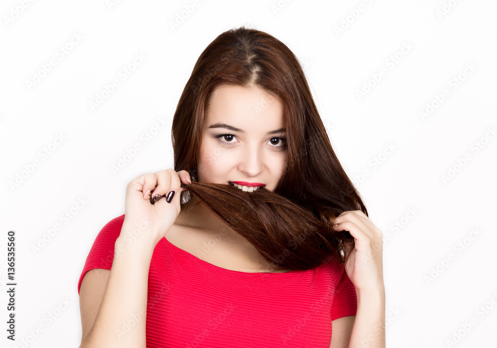 beautiful young woman dressed in a red dress, holds and bites pigtails. studio shot beautiful young woman dressed in a red dress, holds and bites pigtails. studio shot