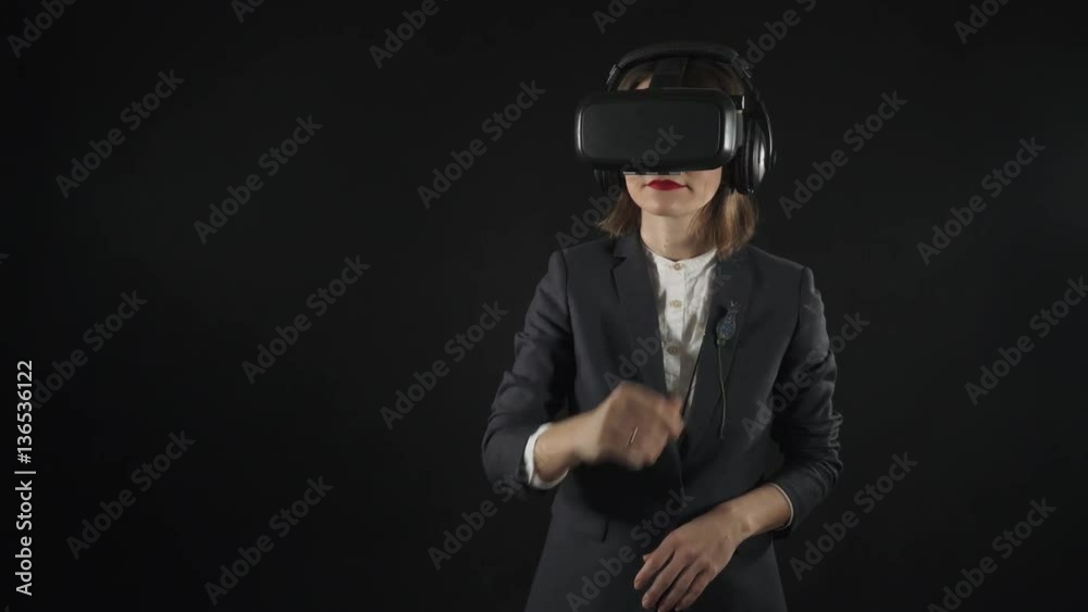 Woman in suit uses virtual reality goggles. Virtual reality helmet with headphones. 4K
Woman uses virtual interface. High-tech devices. The movement of the hands on a black background. Woman in suit uses virtual reality goggles. Virtual reality helmet with headphones. 4K
Woman uses virtual interface. High-tech devices. The movement of the hands on a black background.