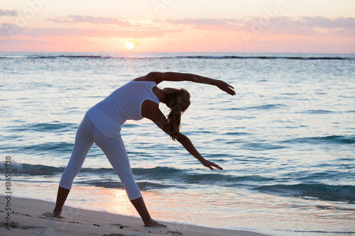femme qui fait  de la gymnastique sur la plage au coucher du soleil