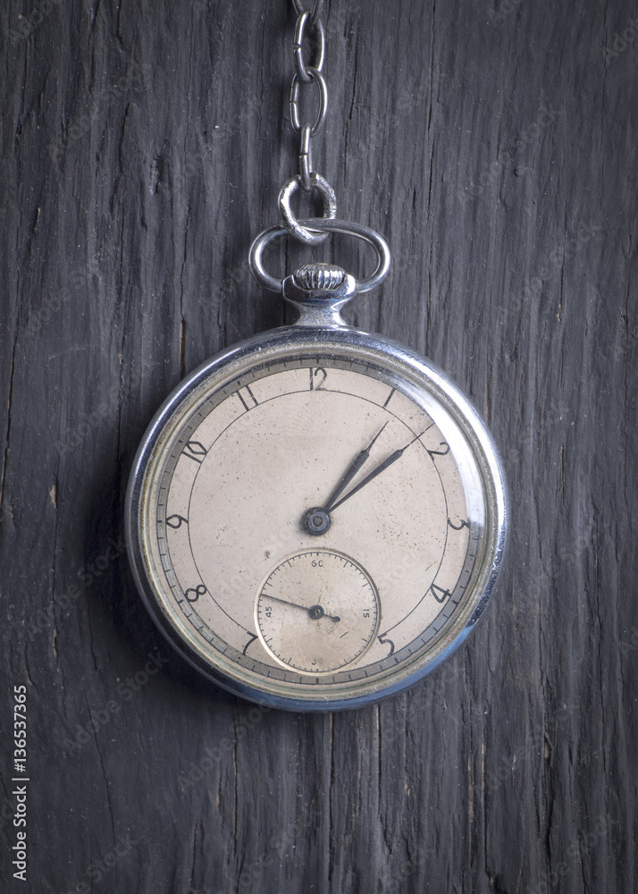Antique clock on an old chain on a dark wooden background