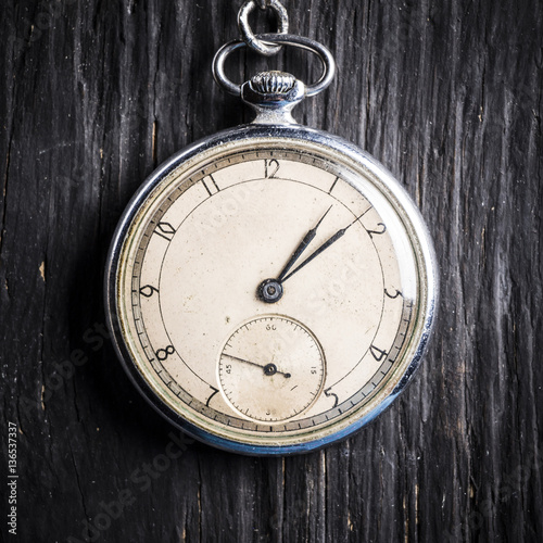 Antique clock on an old chain on a dark wooden background