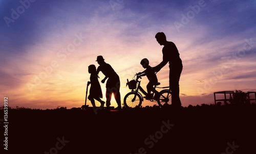 Happy asian family playing at grass on sunset