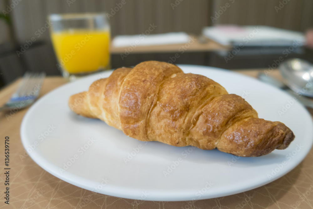 Delicious breakfast with fresh croissants on white plate and ora