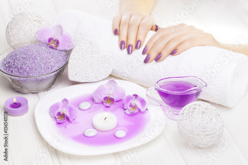 beautiful pink manicure with orchid and towel on the white wooden table. spa