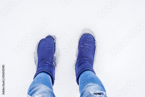 Legs of woman walking in winter park evening. Girl in sheepskin