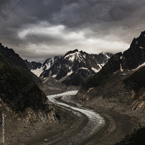 Mountain covered with clouds and glacier's path beneath