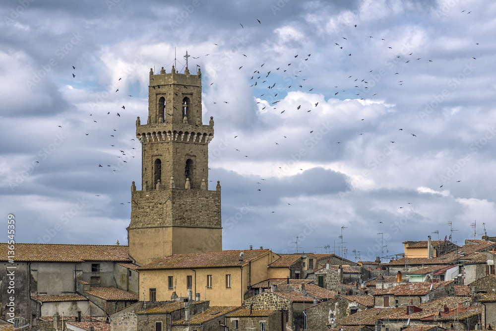 A flock of birds flies over the historic center of the tuff village Pitigliano, Grosseto, Tuscany, Italy