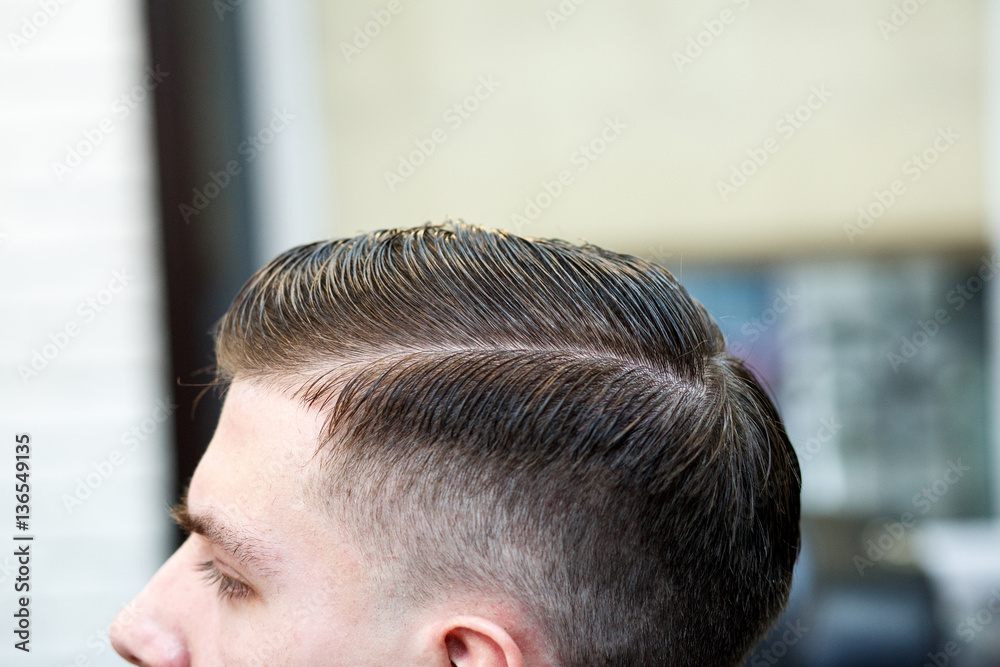 Fototapeta premium Master cuts hair of men in the barbershop, hairdresser makes hairstyle for a young man