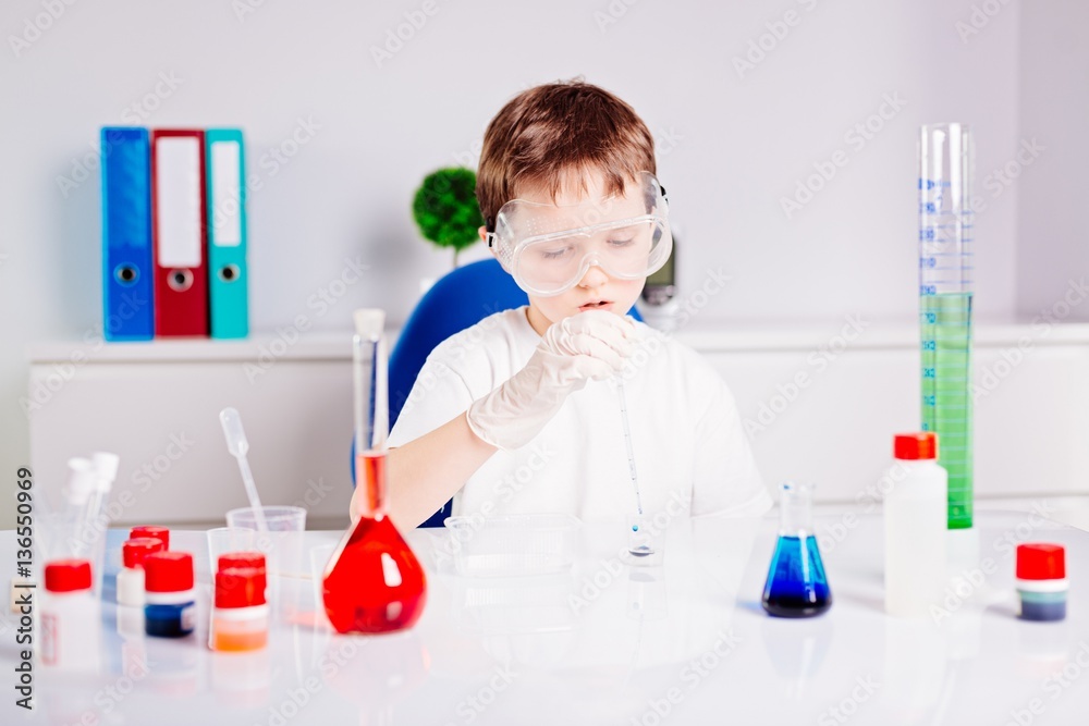 Boy mixing colored liquids in test tubes Boy mixing colored liquids in test tubes