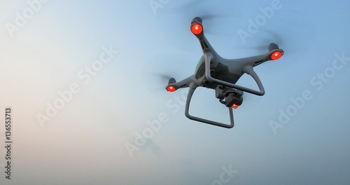 Drone with camera flies in the blue evening sky. photo