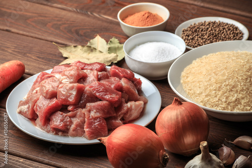 Cooking ingredients. Sliced raw meat, rice, spices, garlic, carrot, onion, bay