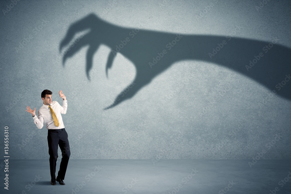 Obraz premium Business person afraid of a big monster claw shadow concept