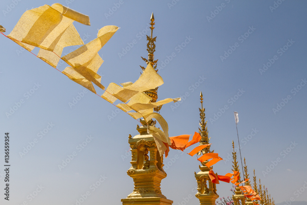 Flying and waving yellow and orange buddhist flags in thai temple with sky background 