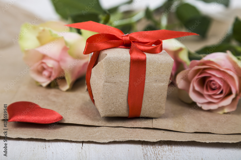 Pink roses,  gift and hearts on a wooden background.