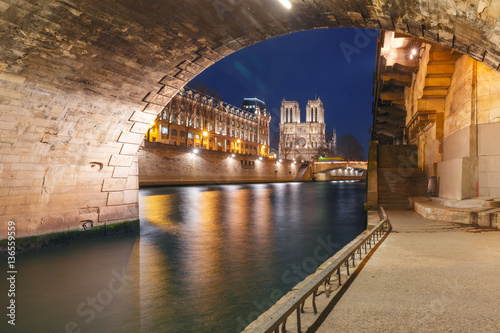 Cathedral of Notre Dame, Petit Pont and riverside of Seine river in Paris at night, France © Kavalenkava