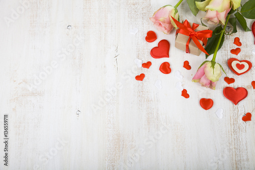Pink roses, gift and hearts on a wooden background.