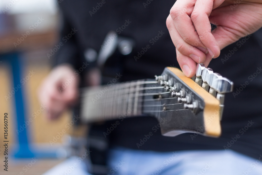 Fototapeta premium Close up of guitarist hand tuning electric guitar