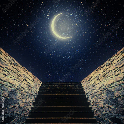 staircase rises to the moon in the night sky.