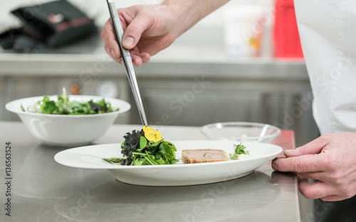 Koch in Restaurant garniert Salat und Pastete mit Bl  ten