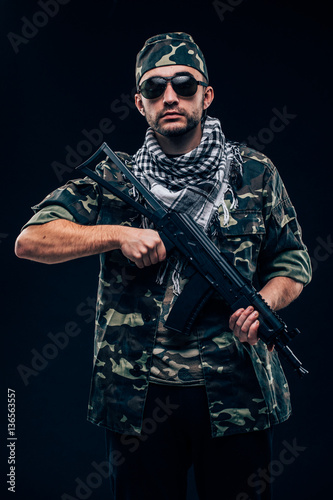 Portrait of a heavily armed masked soldier with black background concept