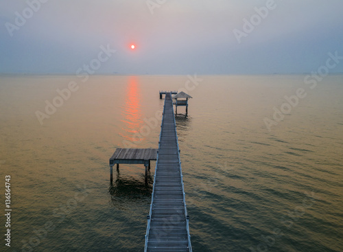wooden bridge laying into the sea at scenery sunset